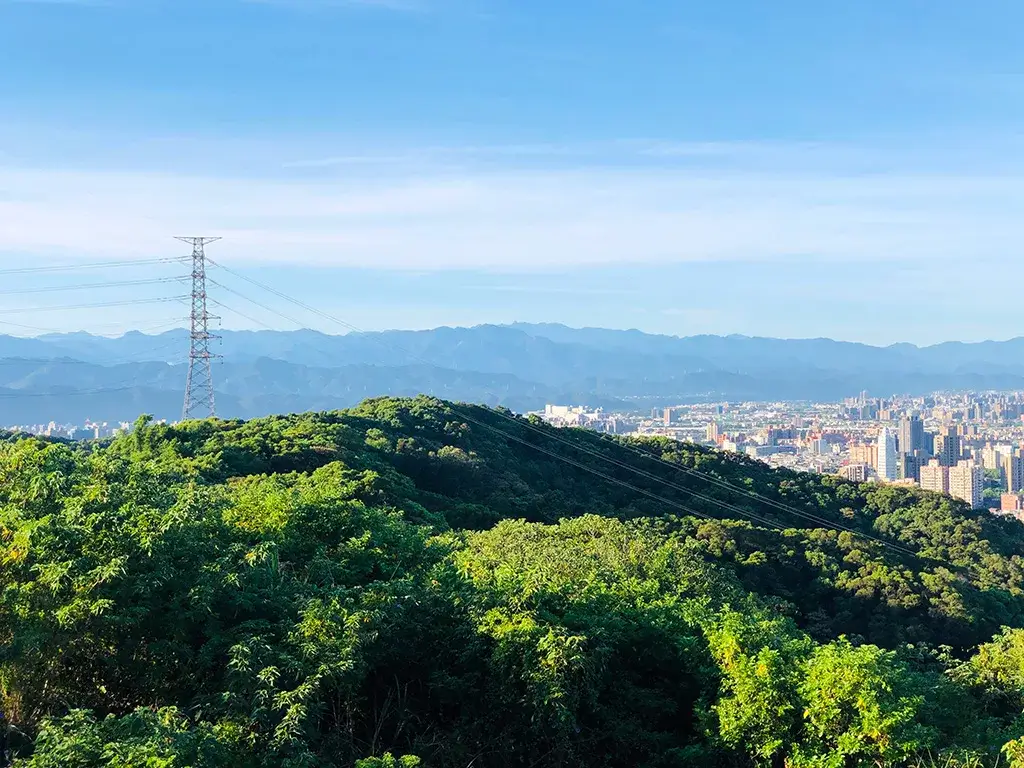 虎頭山環保公園觀景視野，前方綠林、後方城市天際線與山脈。