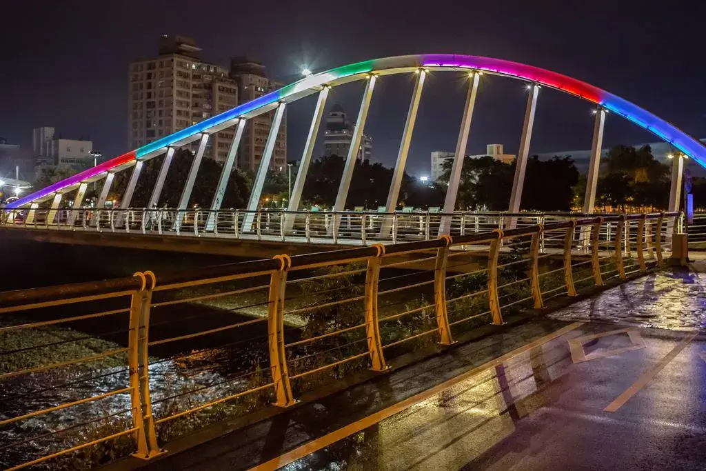 南崁溪水岸自行車道夜景，彩虹拱橋照明映在河面。