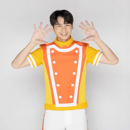 黃橘色制服上衣的男孩，雙手張開於臉旁做手勢微笑，白色背景。