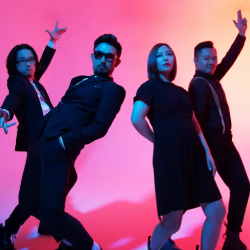 四位樂團成員穿黑色服裝在粉紅藍色漸層燈光前擺出動感姿勢，前方男子戴墨鏡。