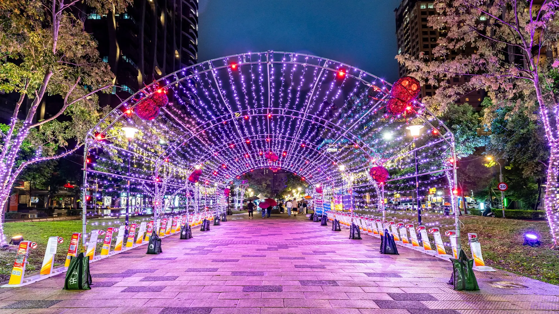 紫色燈海隧道，蛛網與巨型蜘蛛環繞，前景停放公共腳踏車