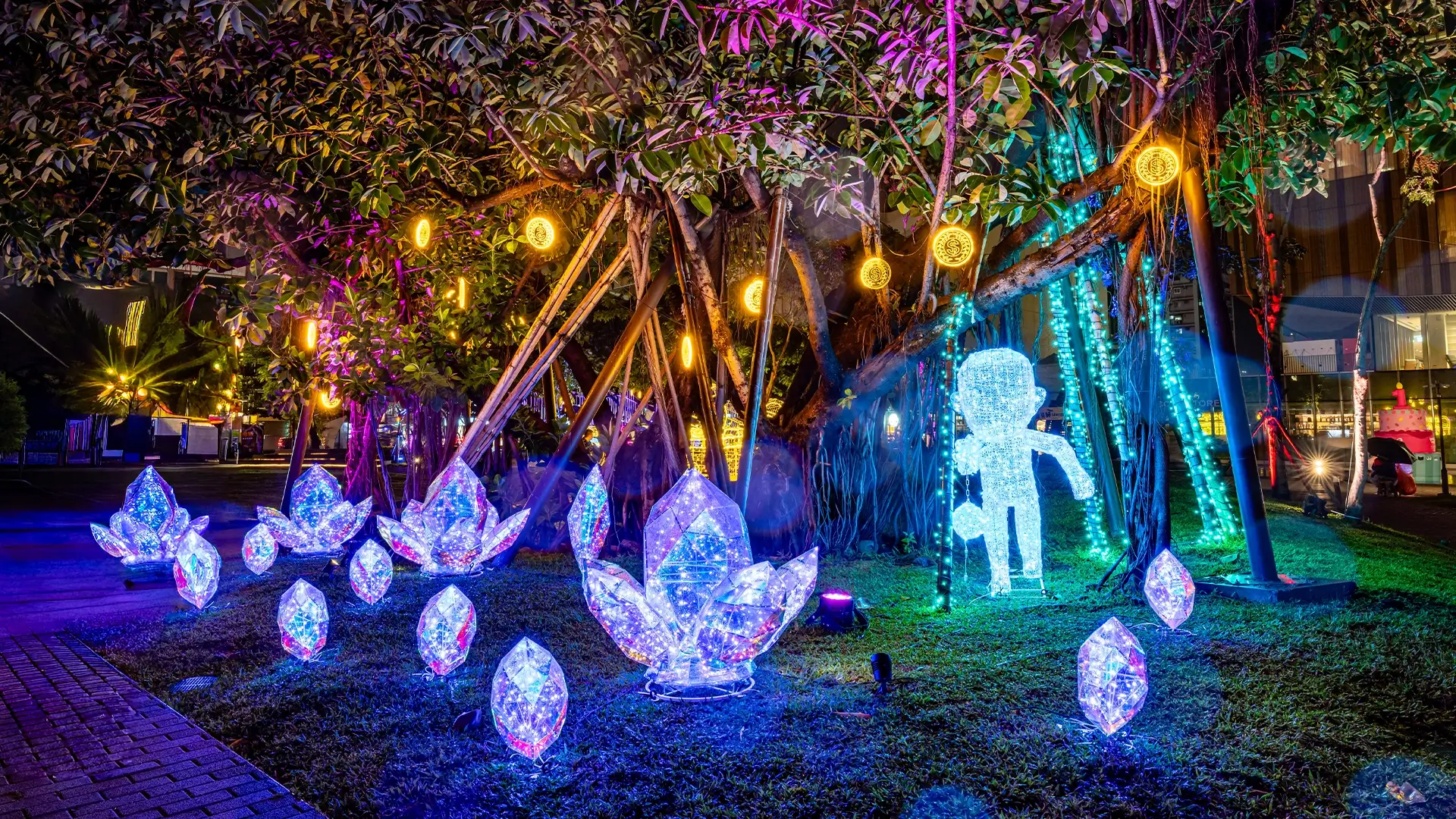 藍黃雙色燈景下，木乃伊與巨網於樹旁，地面散落發光水晶與金幣燈飾